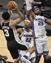 San Antonio Spurs' Keldon Johnson (3) looks to pass the ball as Sacramento Kings' Buddy Hield (24) and Richaun Holmes defend during the first half of an NBA basketball game Wednesday, March 31, 2021, in San Antonio. (AP Photo/Darren Abate)