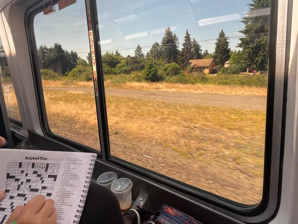 the writer doing a crossword puzzle while looking out the window of the observation car