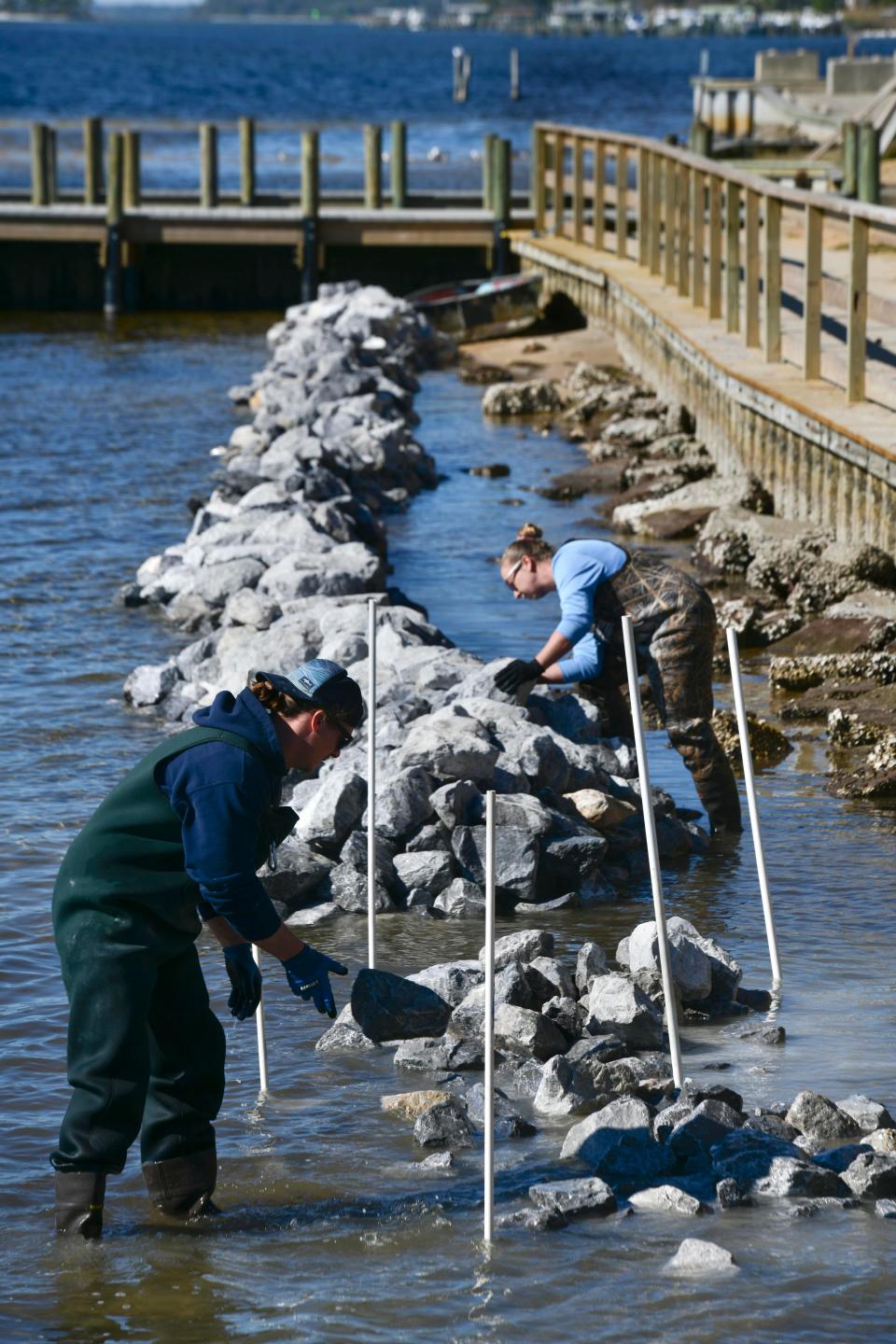 Brennan Wehrhahn and Rachel Gwin with the Choctawhatchee Basin Alliance assemble a limestone breakwater at Liza Jackson Park. When completed, the breakwater will extend along most of the park's waterfront.