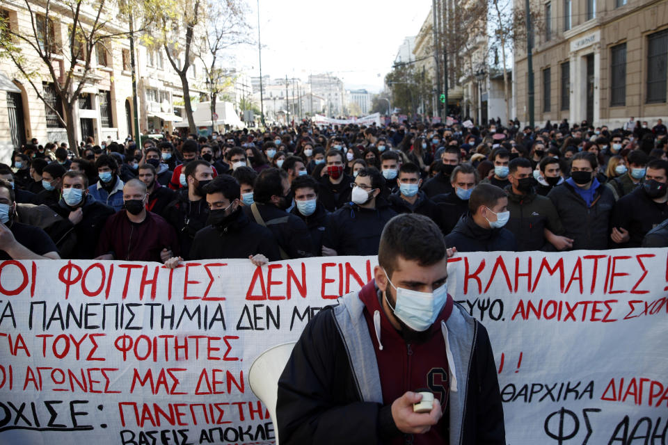 University students gather during a rally against educational reforms as the banner reads "The students are not criminals" in Athens, Thursday, Jan. 21, 2021. About 1,500 students took part in two separate protests against government's plans to set up a state security division at university campuses and time limits set for the completion of degree courses. (AP Photo/Thanassis Stavrakis)