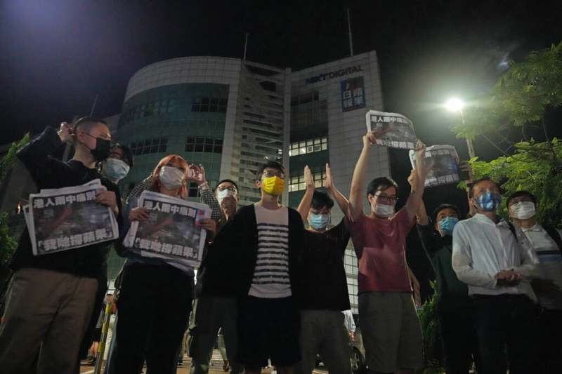 2021年6月24日凌晨，香港《蘋果日報》的員工走出位於將軍澳的總部大樓，手持最後一期報紙向市民鞠躬致謝。（美聯社）