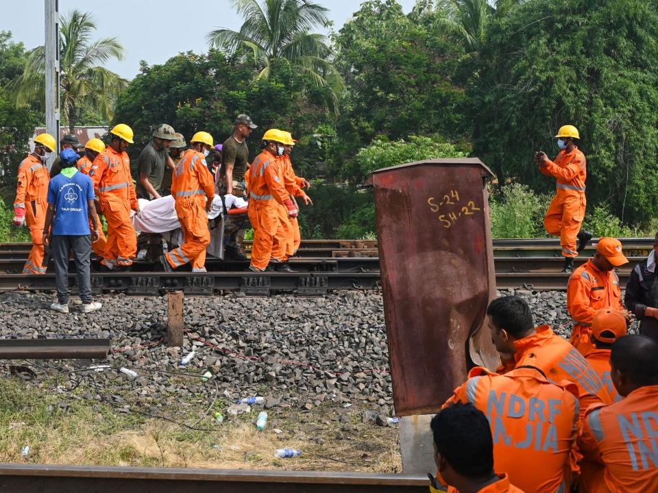 Rescue workers carry the body of a victim along the tracks at the accident site of a three-train collision near Balasore.