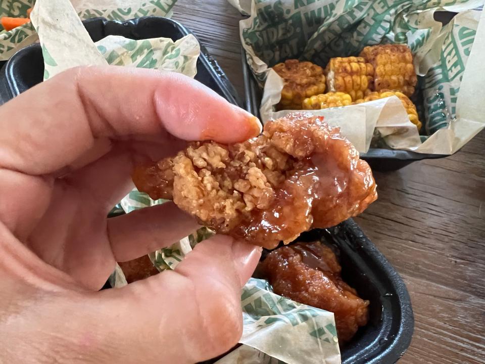 The writer holds a Hawaiian boneless wing with a light-brown sauce on it