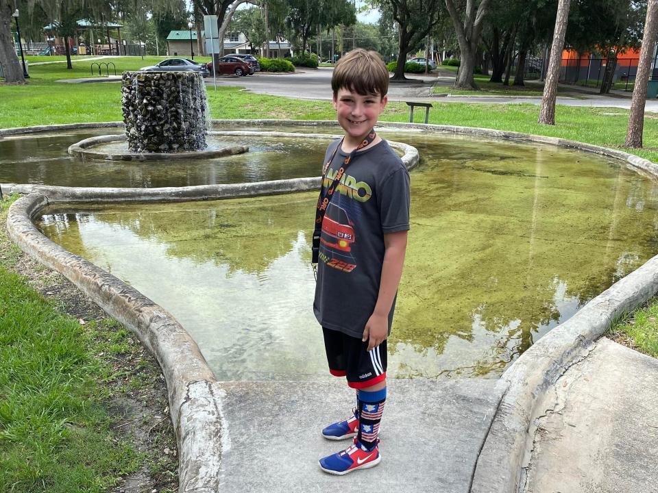 Ashley Archambault's son by a water fountain in a park.