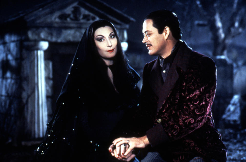 Anjelica Huston and Raul Julia sharing a romantic moment.