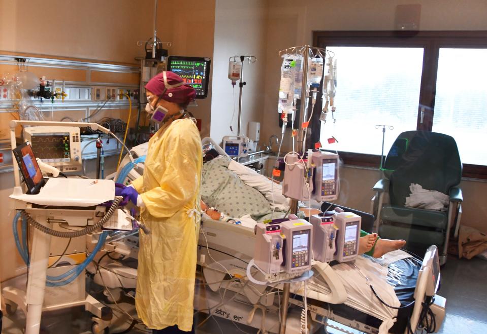 Inside the ICU at Parrish Medical Center, Katie Driver, RN, in protective clothing, treats a COVID-19 patient. 