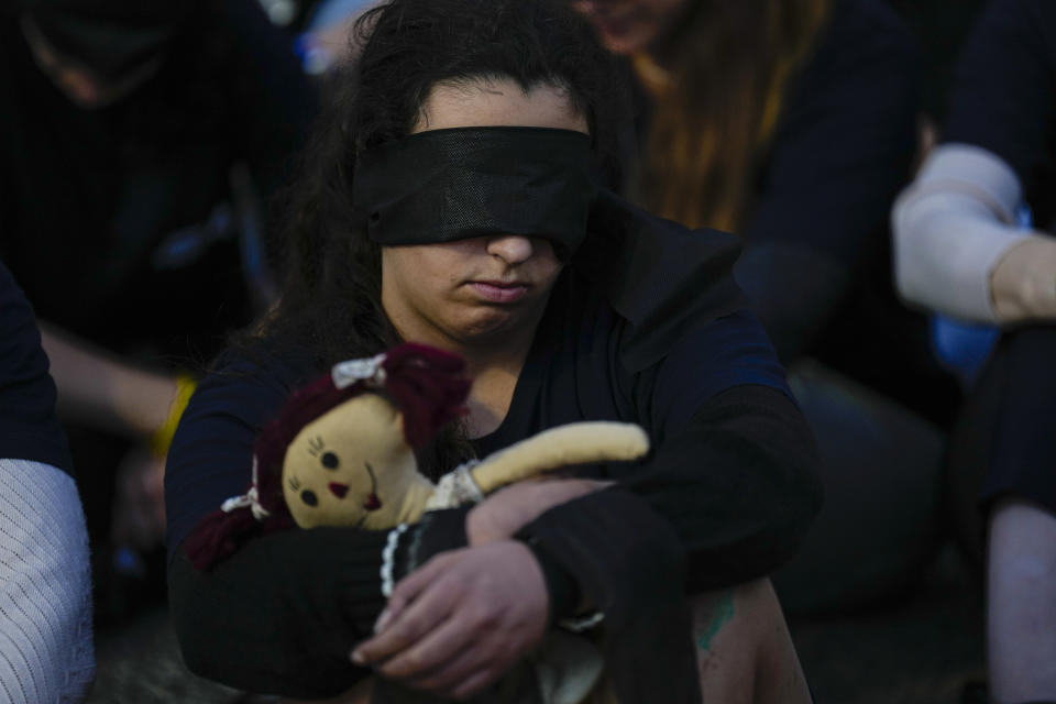 Relatives and friends of hostages held in the Gaza Strip by the Hamas militant group have their eyes covered as a display to show the condition of the hostages while they call for their release during the Jewish holiday of Hanukkah in the Hostages Square at the Museum of Art in Tel Aviv, Israel, Monday, Dec. 11, 2023. (AP Photo/Ariel Schalit)