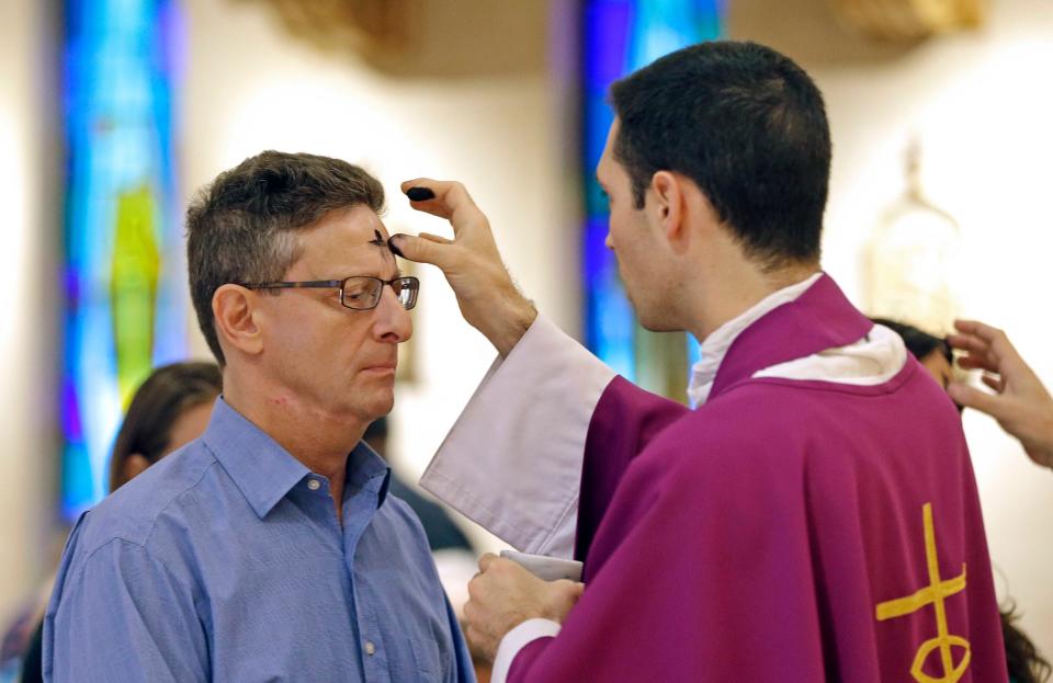Father Martin Guyot places the sign of the cross in ashes on the forehead of worshiper Paul A. Zilio at Blessed Trinity Catholic Church, Wednesday, March 1, 2017, in Virginia Gardens, Fla.