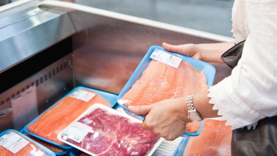 Housewife buying a tray of fresh salmon.