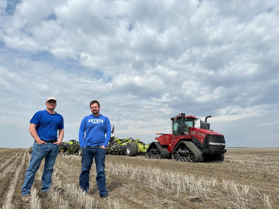 Left to right, Steve and Scott Heeg stand in a field where they were seeding canola this spring. The brothers farm in Acadia Valley in eastern Alberta.