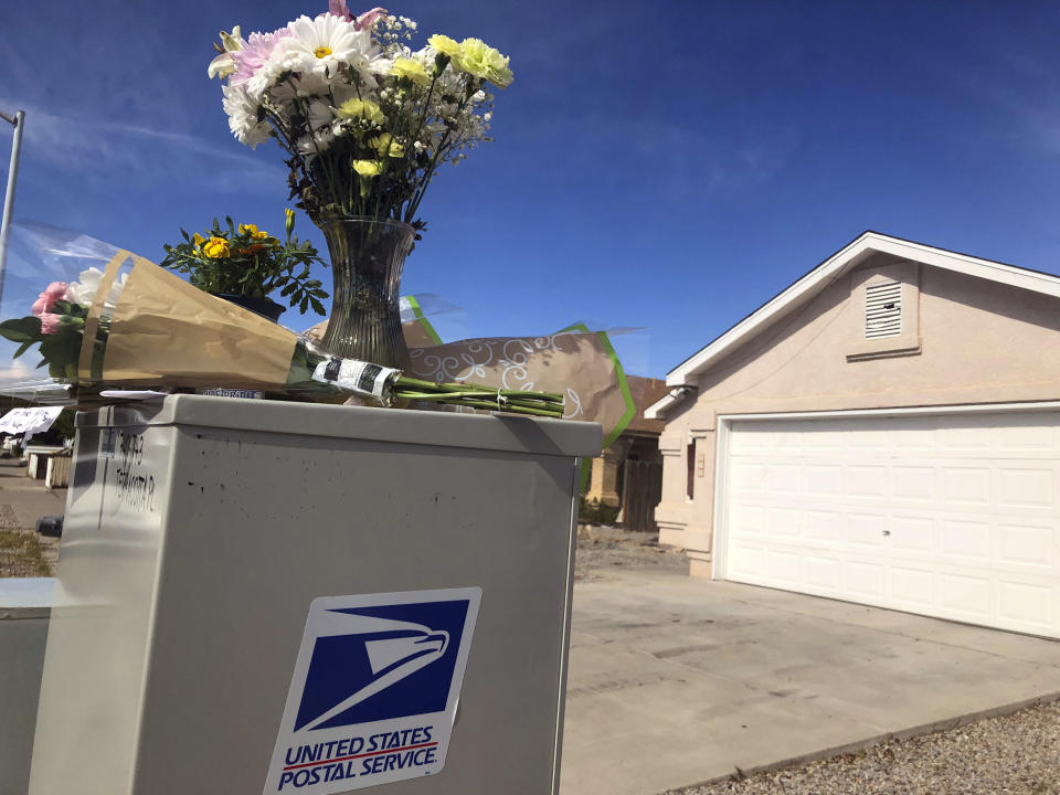 Flowers and notes are arranged atop a mailbox on Tuesday, April 23, 2019, in tribute to a mail carrier who police say was killed outside an adjacent home in Albuquerque, N.M. Police said in a criminal complaint that the mail carrier was fatally shot Monday, April 22, while trying to intervene in a dispute between a mother and her 17-year-old son, who has been identified as the shooting suspect. (AP Photo/Mary Hudetz)