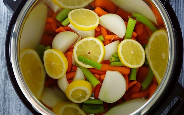 placing vegetables, lemon and broth in instant pot before adding the raw turkey breast