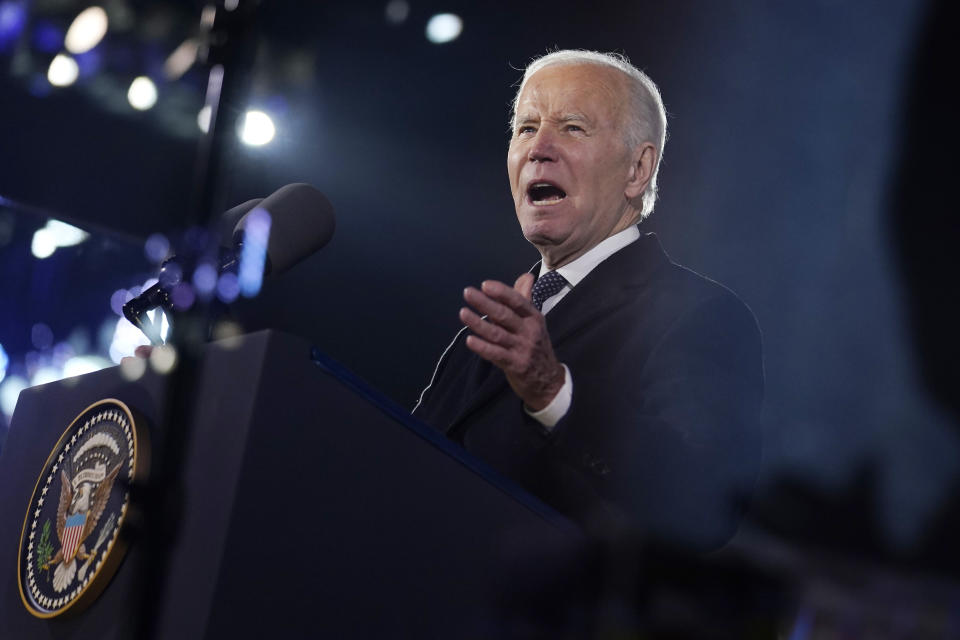 Biden gestures with his left hand as he speaks at a podium.