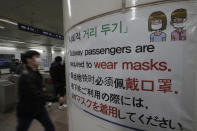 People wearing face masks as a precaution against the coronavirus, walk past a banner at a subway station in Seoul, South Korea, Friday, Nov. 13, 2020. South Korea has reported its biggest daily jump in COVID-19 cases in 70 days as the government began fining people who fail to wear masks in public. From Friday, officials started to impose fines of up to 100,000 won ($90) for people who fail to properly wear masks in public transport and a wide range of venues, including hospitals, nursing homes, pharmacies, nightclubs, karaoke bars, religious and sports facilities and at gatherings of more than 500 people. (AP Photo/Lee Jin-man)