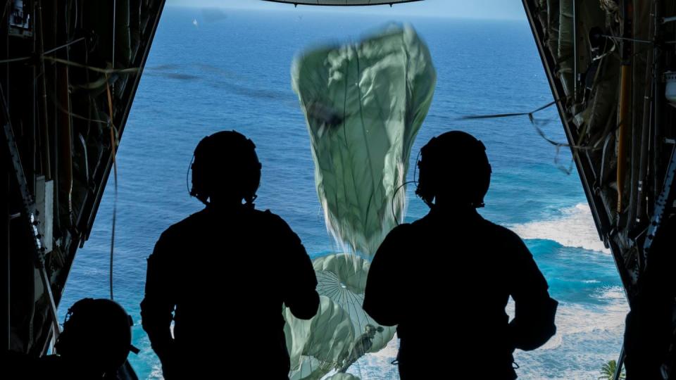 U.S. Air Force loadmasters watch as parachutes open on supply crates dropped from a C-130J during Operation Christmas Drop on Dec. 5, 2022. (Staff Sgt. Jerreht Harris/U.S. Air Force)