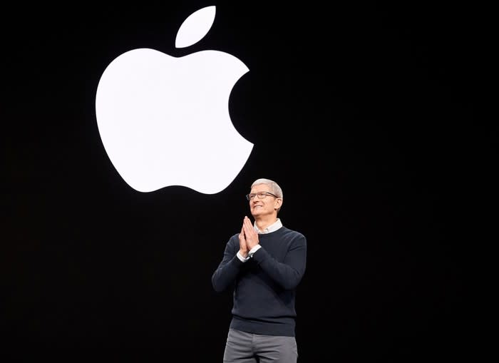 Apple CEO Tim Cook on stage with the Apple logo on the screen behind him