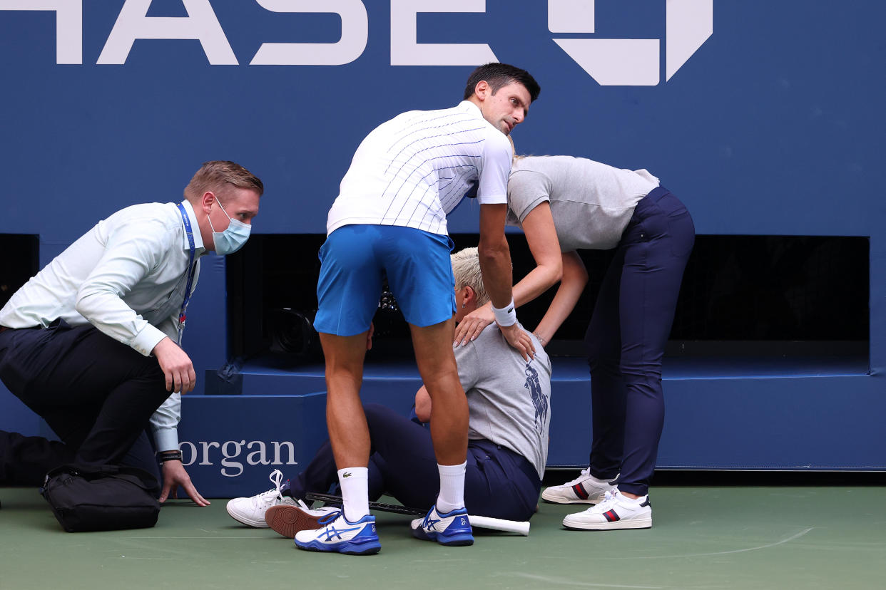 Novak Djokovic helps the line judge he hit with a tennis ball.