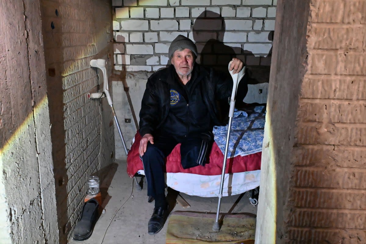 An elderly disabled man sits on a bed as residents of a building, partially destroyed after shelling in Kharkiv (AFP via Getty Images)