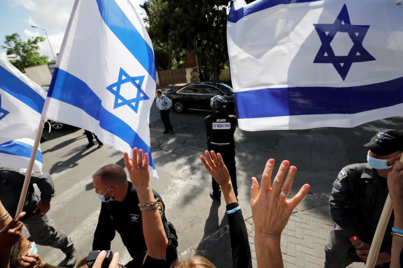 Supporters of Israeli Prime Minister Benjamin Netanyahu wave Israeli flags as Netanyahu's convoy passes after the end of a court session in Netanyahu's corruption trial, near the Jerusalem District Court