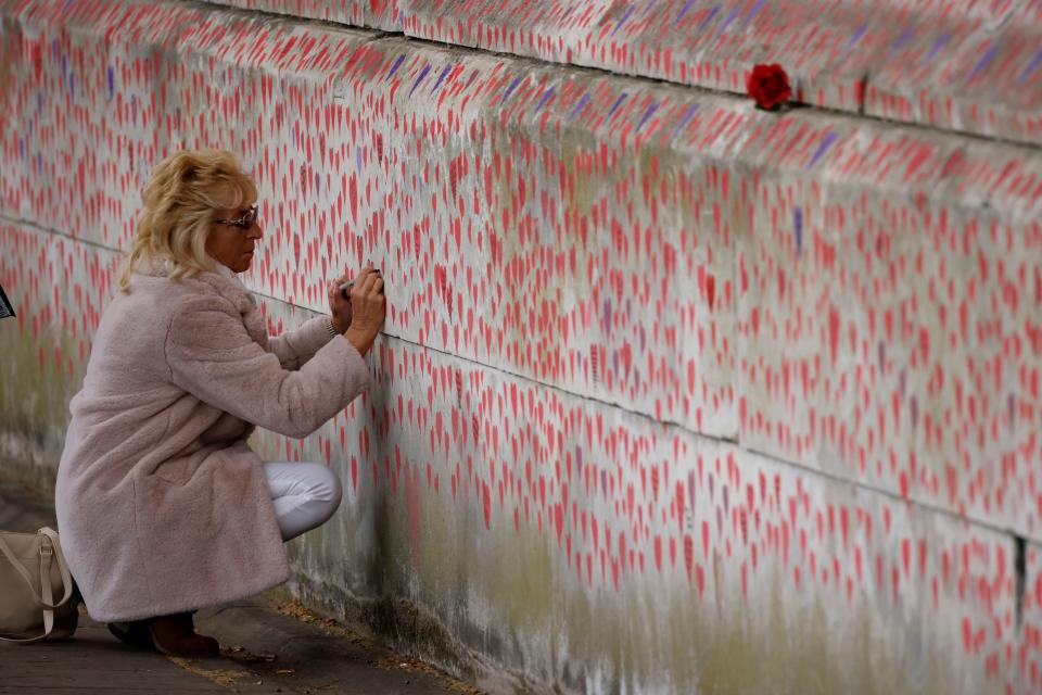 <p>A woman draws on the National Covid Memorial Wall on the embankment on the south side of the River Thames in London on April 30, 2021 in memory of those who lost their lives to Covid-19. (Photo by Tolga Akmen / AFP) (Photo by TOLGA AKMEN/AFP via Getty Images)</p>
