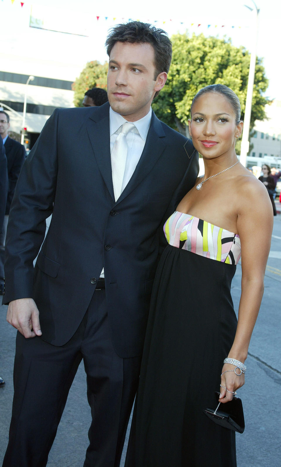 Ben Affleck and Jennifer Lopez at an event. He's in a suit; she's wearing a strapless dress with a multi-colored top section