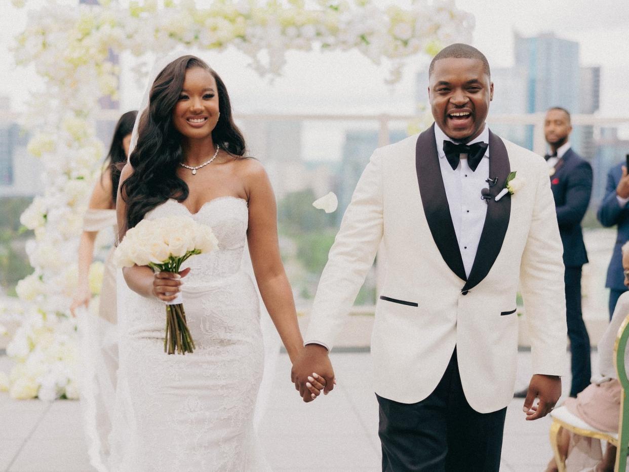 A bride and groom hold hands as they exit their wedding ceremony.