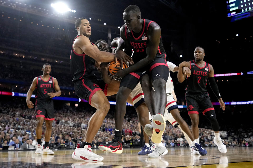 Connecticut forward Adama Sanogo, center, vies for the ball with San Diego State forward Jaedon LeDee, left, and forward Aguek Arop during the first half of the men's national championship college basketball game in the NCAA Tournament on Monday, April 3, 2023, in Houston. (AP Photo/Brynn Anderson)