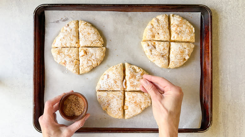 Sprinkling turbinado sugar on peaches and cream scone dough on baking sheet