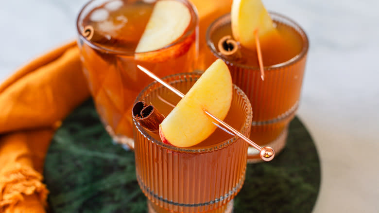 Three kombucha glasses with garnish on green tray