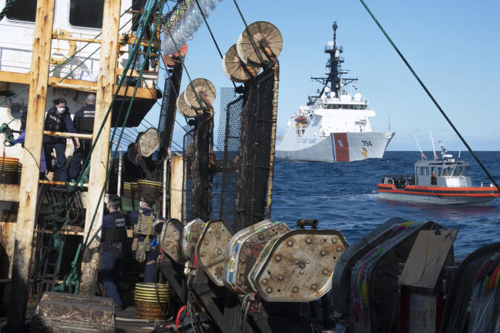 In this photo made available by the U.S. Coast Guard, guardsmen from the cutter James, seen at background right, conduct a boarding of a fishing vessel in the eastern Pacific Ocean, on Aug. 4, 2022. During the 10-day patrol for illegal, unreported or unregulated fishing, three vessels steamed away. Another turned aggressively 90 degrees toward the James, forcing the American vessel to maneuver to avoid being rammed. (Petty Officer 3rd Class Hunter Schnabel/U.S. Coast Guard via AP)