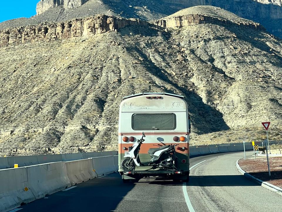 bus driving on small road with mountains in the back