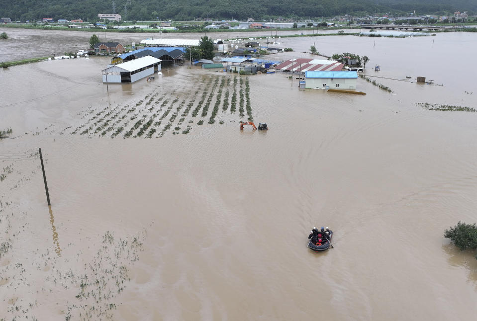 Rescue workers on a boat search for missing people in floodwaters caused by the tropical storm named Khanun in Daegu, South Korea, Thursday, Aug. 10, 2023. Khanun was pouring intense rain on South Korea on Thursday, turning roads into chocolate-colored rivers as it advanced north toward major urban centers near the capital. (Yun Kwan-shick/Yonhap via AP)