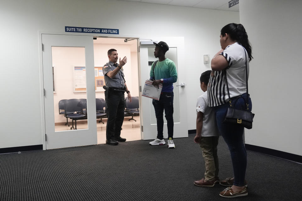 FILE - An officer directs people to a courtroom, Jan. 10, 2024, in an immigration court in Miami. A 53-year-old union of immigration judges has been ordered to get supervisor approval to speak publicly to anyone outside the Justice Department, potentially quieting a frequent critic of heavily backlogged immigration courts in an election year. (AP Photo/Wilfredo Lee, File)