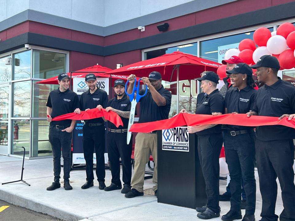 General Manager DaShawn Johnson, center, cuts a red ribbon Monday, Oct. 23, 2023, celebrating the opening of Five Guys in Machensey Park, the restaurant chain's second Rockford-area location.