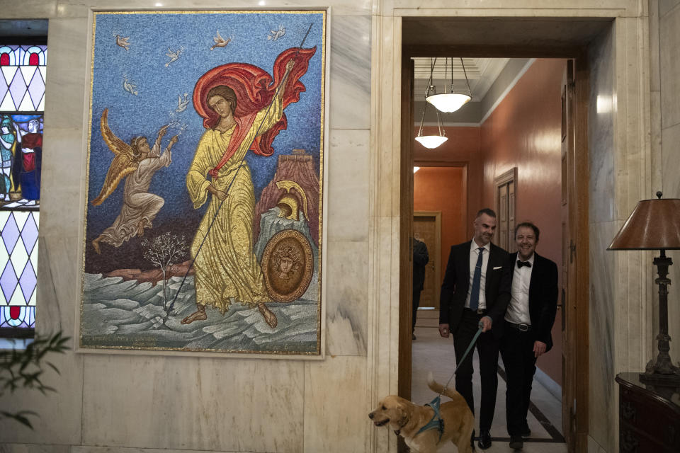 Greek author Petros Hadjopoulos, who uses the pen name Auguste Corteau, right and his husband, lawyer Anastasios Samouilidis, leave with their dog Jerry, after their wedding at Athens City Hall, Greece, on Thursday, March 7, 2024. A Greek novelist and his partner on Thursday became the first male couple to be married in Athens' city hall following the legalization of same-sex marriage in Orthodox Christian Greece. (AP Photo/Michael Varaklas)