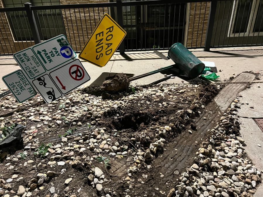 Damage to cars, street signs, etc. along East 9th Street near Embassy Drive after an 18-wheeler crashed into 10 parked vehicles overnight April 22, 2024 (KXAN Photo/Todd Bailey)