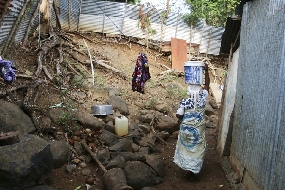 A woman carries a bucket of water on her head in the district of M'tsamoudou, near Bandrele, on the French Indian Ocean territory of Mayotte, Thursday, Oct. 12, 2023. Water taps flow just one day out of three because of a drawn-out drought compounded by years of water mismanagement. (AP Photo/Gregoire Merot)