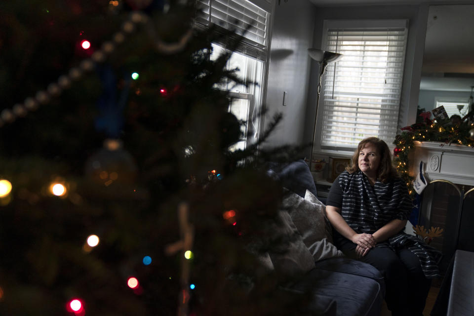 Eileen Carroll sits for a portrait in her home in Warwick, R.I, Wednesday, Dec. 16, 2020. When Carroll's daughter tested positive for the coronavirus, state health officials told her to notify anyone her daughter might have been around. Contact tracers, she was told, were simply too overwhelmed to do it. It's the same story across the U.S., as a catastrophic surge in infections has made it difficult or impossible to keep up with the calls considered critical to controlling outbreaks. (AP Photo/David Goldman)