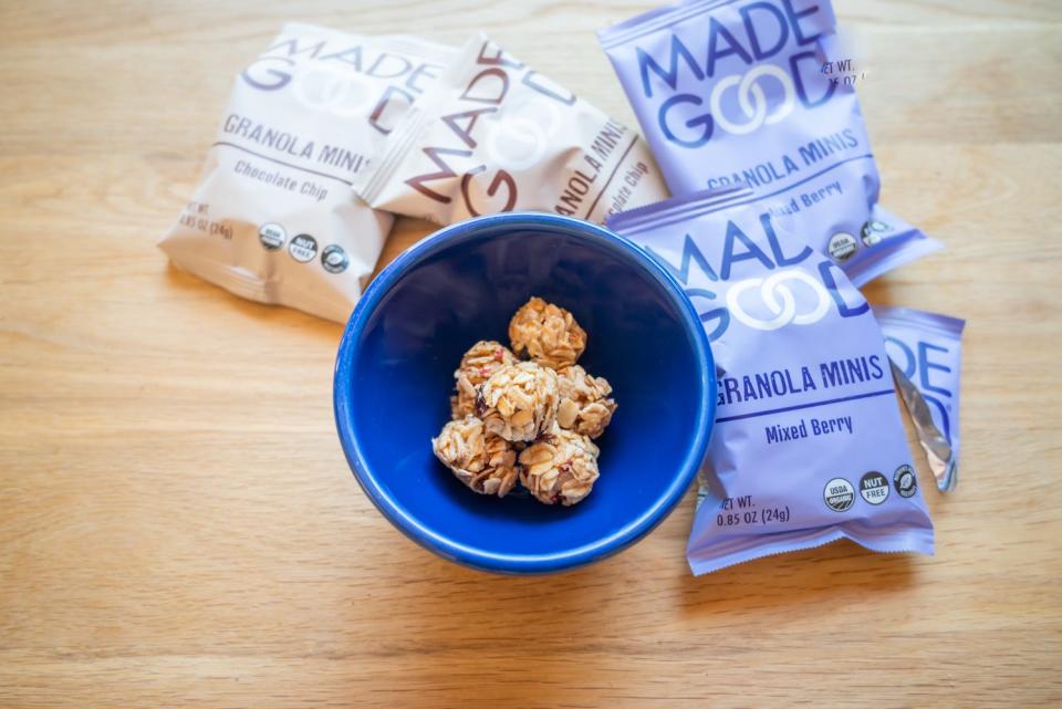 madegood granola bites in blue bowl surrounded by madegood packages on wood table