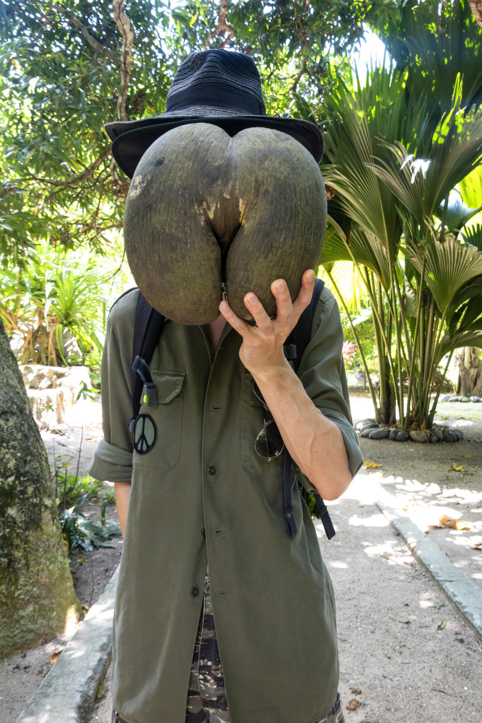 Someone holding the seed — which looks a bit like the backs of two thighs and buttocks — in front of their face