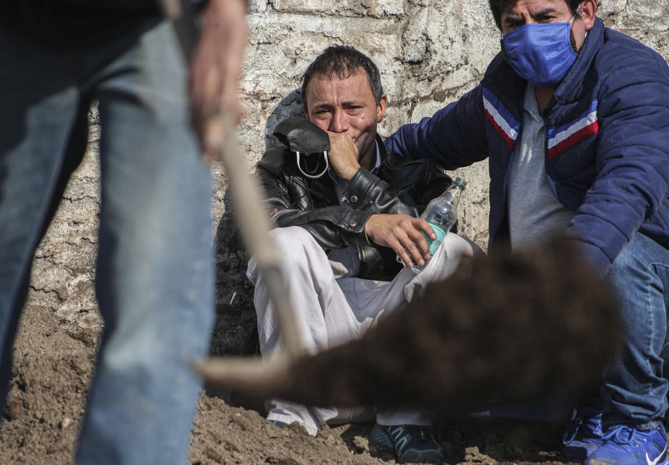 El migrante peruano José Collantes llora mientras observa a los trabajadores del cementerio que entierran a su esposa Silvia Cano, quien falleció por complicaciones relacionadas con COVID-19, según Collantes, en el cementerio católico en Santiago de Chile, el viernes 3 de julio de 2020. Collantes dijo que prefería cremarla para poder llevarse las cenizas con él, pero debido a la burocracia, ya había esperado por dos semanas. (AP Foto/Esteban Felix)