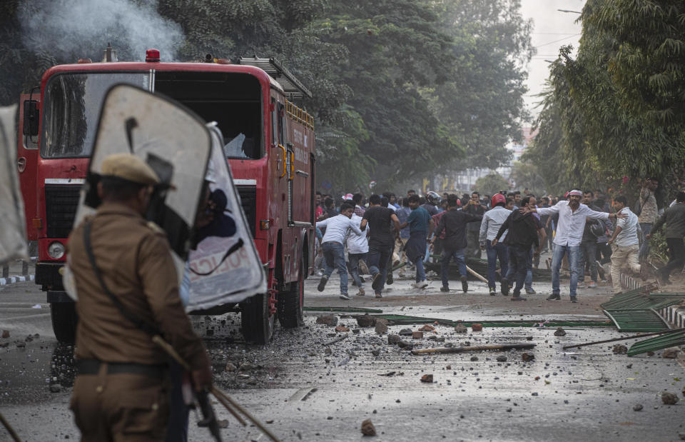 Protestors shout slogans as they face security officers during a protest against the Citizenship Amendment Bill (CAB) in Gauhati, India, Wednesday, Dec. 11, 2019. Protesters burned tires and blocked highways and rail tracks in India's remote northeast for a second day Wednesday as the upper house of Parliament began debating legislation that would grant citizenship to persecuted Hindus and other religious minorities from Pakistan, Bangladesh and Afghanistan. (AP Photo/Anupam Nath)