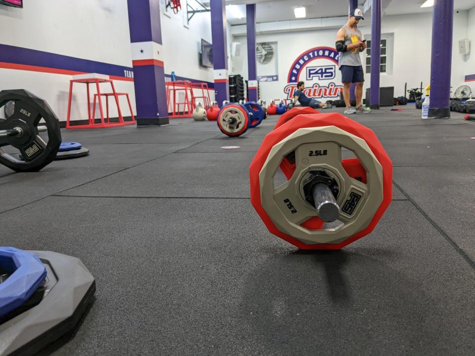 <p>A picture from the Pixel 6a's camera, featuring a barbell with colorful plates in the foreground and a gym in the background.</p>
