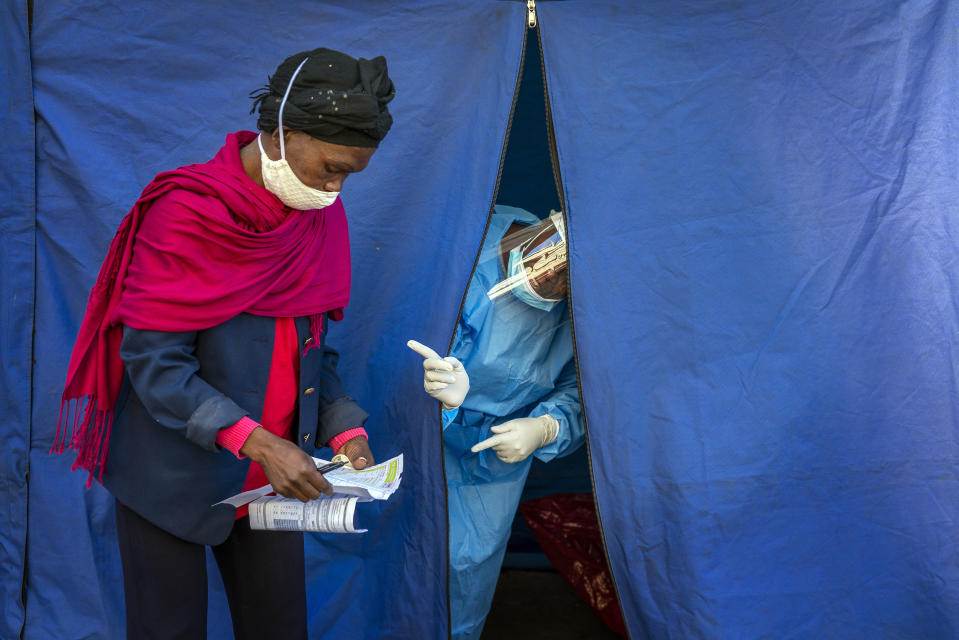 Heath officials check the listings of people who are to be tested for COVID-19 as well as HIV and Tuberculosis, in downtown Johannesburg, April 30, 2020. Thousands are being tested in an effort to derail the spread of coronavirus. (AP Photo/Jerome Delay)