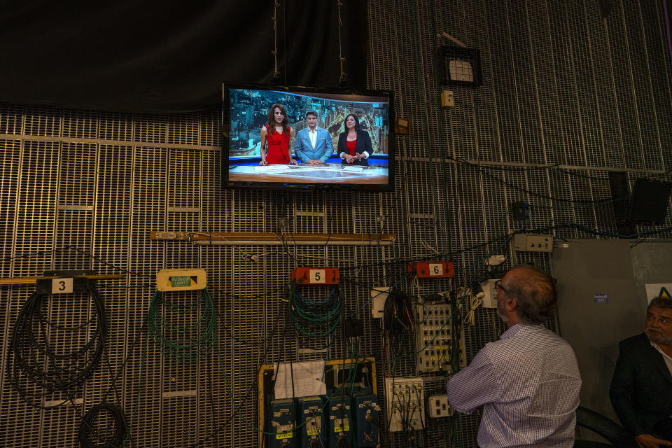 In this March 5, 2020 photo, a producer watches Diana Zurco, dressed in red, during a rehearsal for her debut as the country’s first transgender newscaster, in Buenos Aires, Argentina. Her job as a co-anchor of Public Television's prime time evening news program is a milestone for an excluded community that is often the target of violence and has a life expectancy roughly half that of the rest of the population. (AP Photo/Victor R. Caivano)