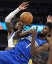 Orlando Magic forward Jonathan Isaac (1) loses control of the ball as he goes up for a shot against Golden State Warriors forward Kevon Looney during the first half of an NBA basketball game Wednesday, March 27, 2024, in Orlando, Fla. (AP Photo/John Raoux)