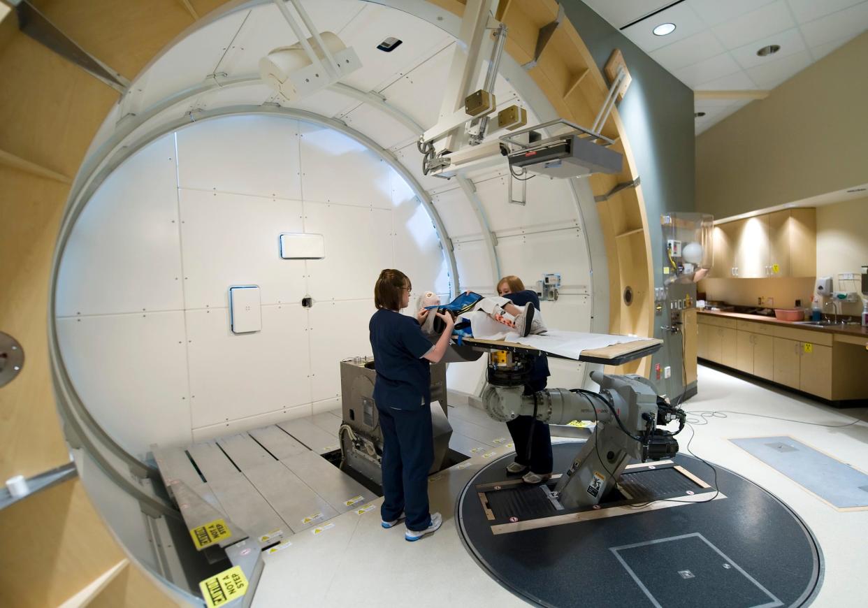Katie Huhta is prepared for her proton therapy treatment at MPRI by radiation therapists Debbie Stockhover (left) and Amanda Scarsdale. The team uses X-ray scans to precisely locate the tumor in Katie's head before each treatment. The Indiana University Health Proton Therapy Center and IU Cyclotron will close no later than Jan. 1, 2015, IU announced Friday. David Snodgress | Herald-Times 