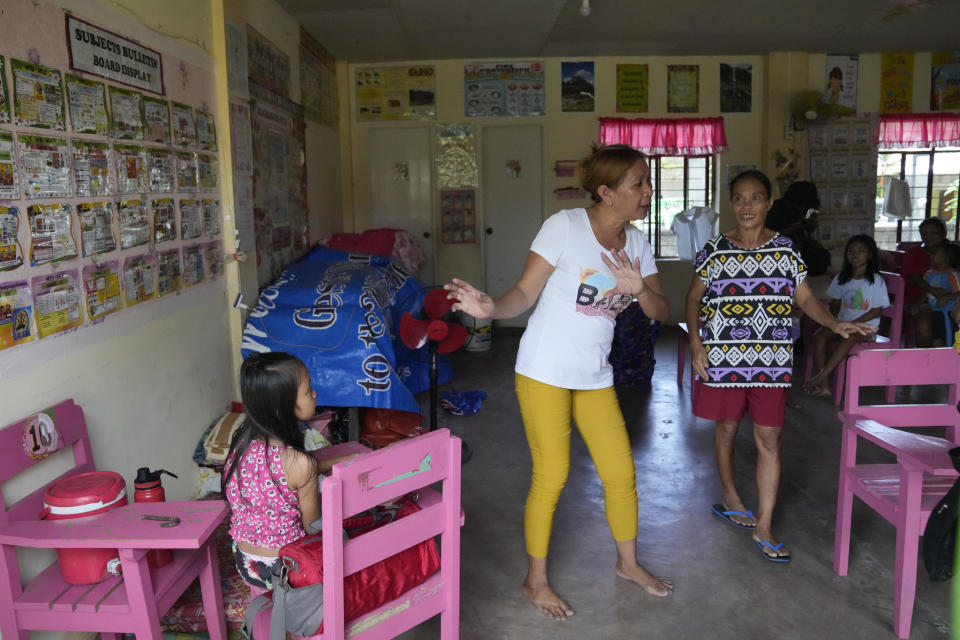 Liza David Balbin, center, gestures inside a school converted into a temporary evacuation center in Santo Domingo town, Albay province, northeastern Philippines, Tuesday, June 13, 2023. In 1991, Balbin witnessed Mount Pinatubo blowing its top in one of the biggest volcanic eruptions of the 20th century. She survived and years later married a man, who took her to his home province of Albay, where they lived in an impoverished village not far from Mayon. (AP Photo/Aaron Favila)