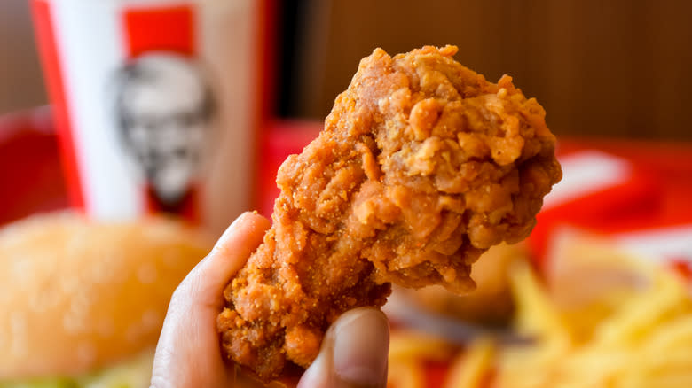 Hand holding chicken drumstick from KFC