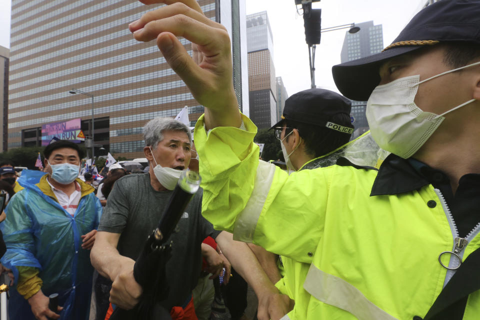 A protester argues with a police officer during a rally against the government in Seoul, South Korea, Saturday, Aug. 15, 2020. Thousands of anti-government protesters, armed with umbrellas and raincoats, marched through the soggy streets of South Korea's capital Saturday, ignoring official pleas to stay home amid a surge in coronavirus infections. (AP Photo/Ahn Young-joon)